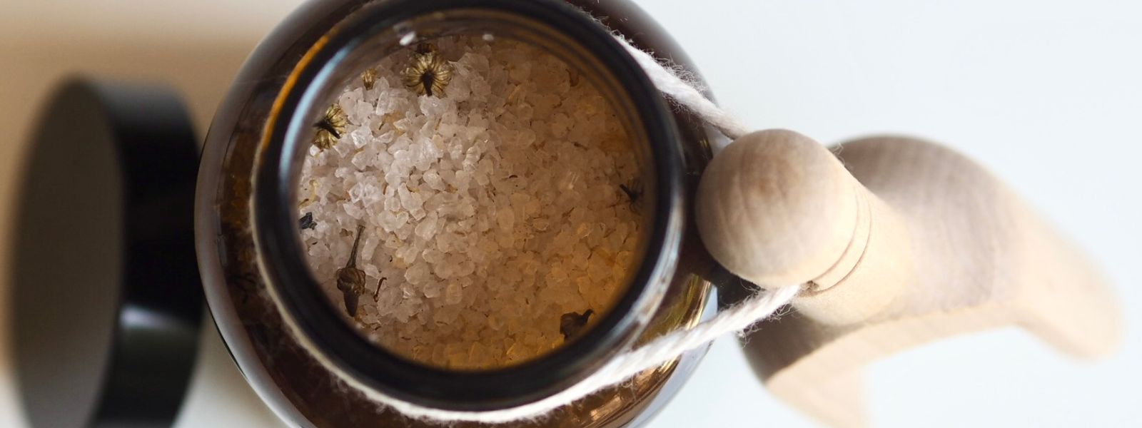 open amber glass jar of Glow Himalayan bath salts with wooden scoop