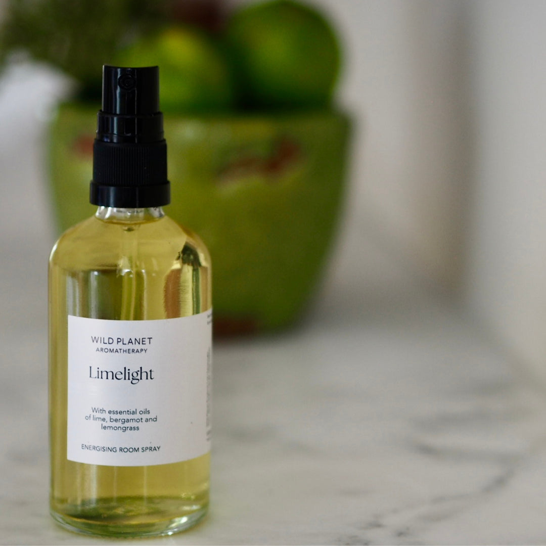 Limelight citrus Aromatherapy Room Spray on marble top in front of green bowl with fresh limes