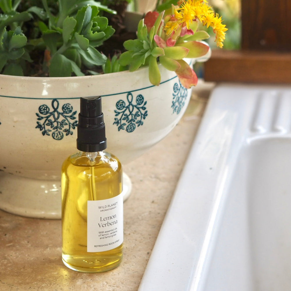 Lemon Verbena Essential Oil Room Spray next to white kitchen sink and bowl of flowers
