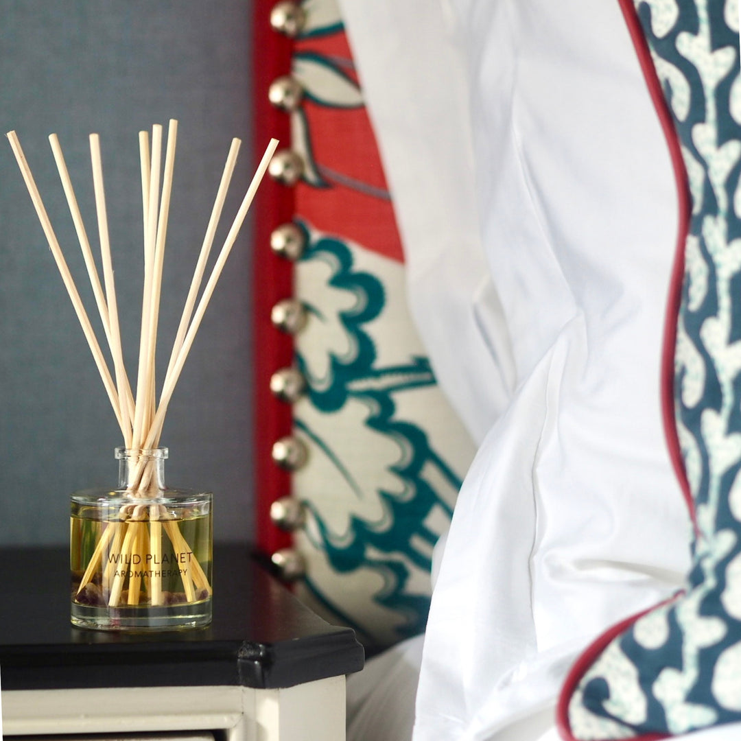 Deep Slumber natural and organic reed diffuser on black and cream bedside cabinet next to bed