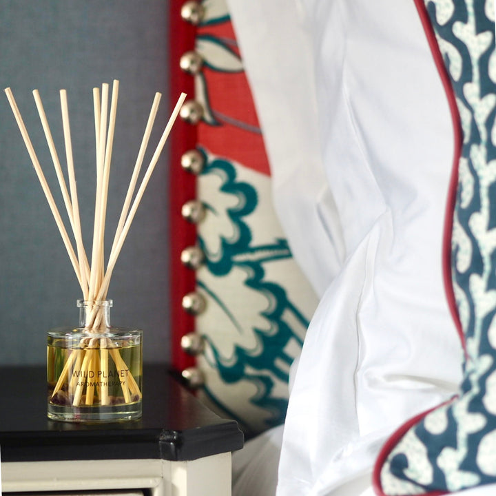 Deep Slumber natural and organic reed diffuser on black and cream bedside cabinet next to bed