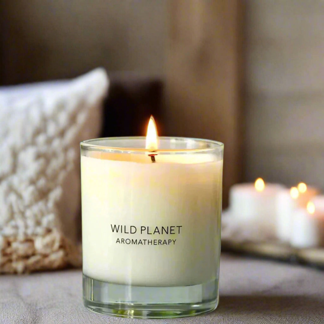 Warm Hug patchouli & vetiver natural candle with cedarwood with flame next to soft cushions