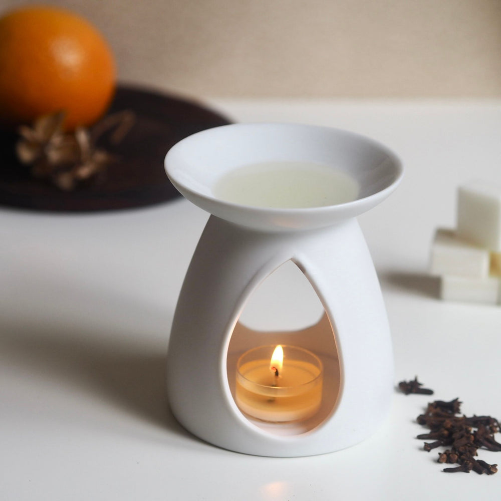 Soft Embers clove orange wax melt melted in white ceramic oil burner, tea light, clove buds & orange