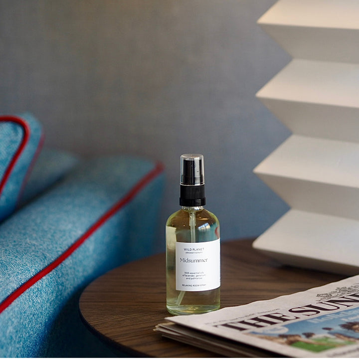 Midsummer lavender Room Spray with geranium and palmarosa essential oils on table next to blue sofa