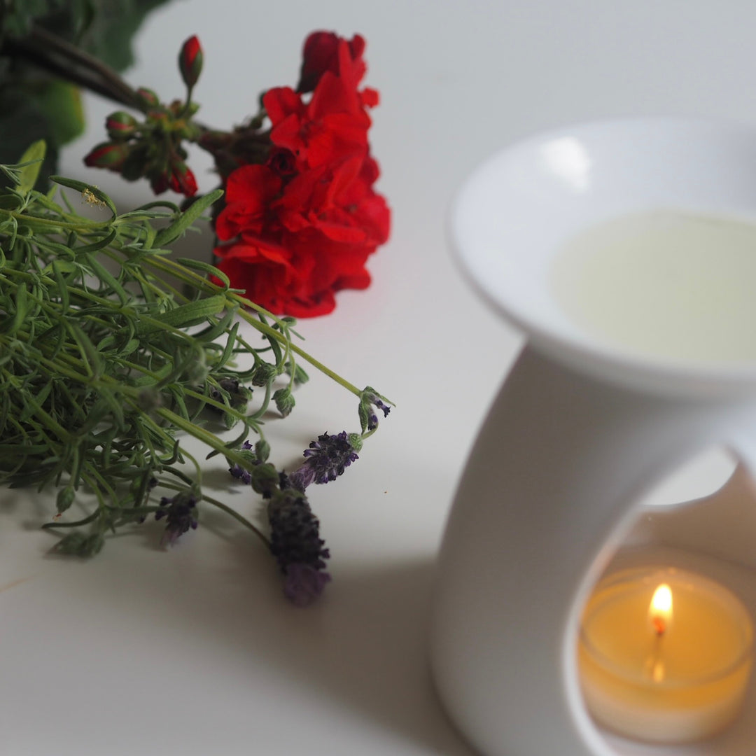 White ceramic oil burner with lit tea light heating Wild Planet luxury wax melt, red flower & herbs