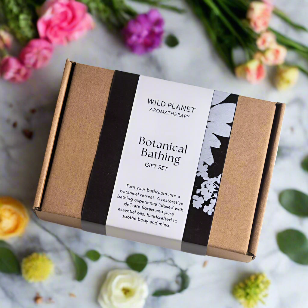 Botanical Bathing Gift Set box next to pretty flowers on grey marble by Wild Planet Aromatherapy