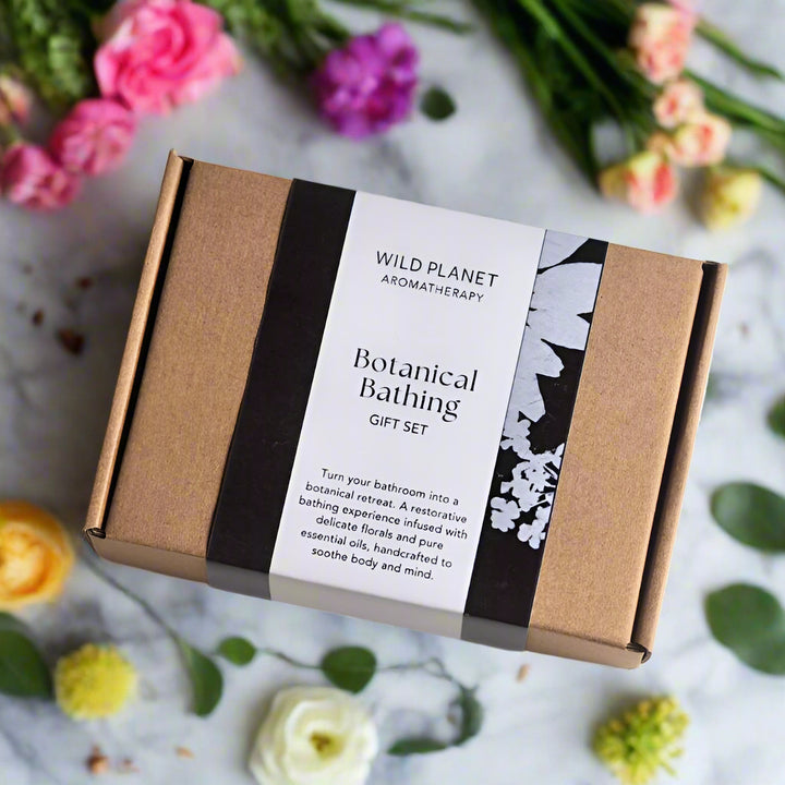 Botanical Bathing Gift Set box next to pretty flowers on grey marble by Wild Planet Aromatherapy