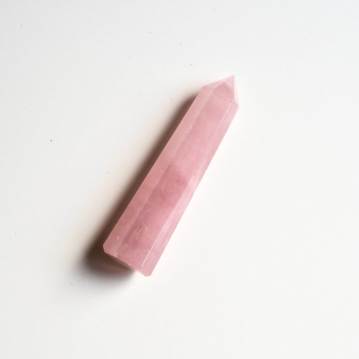 Rose Quartz Crystal Tower lying down on white background to boost calm, love and healing.